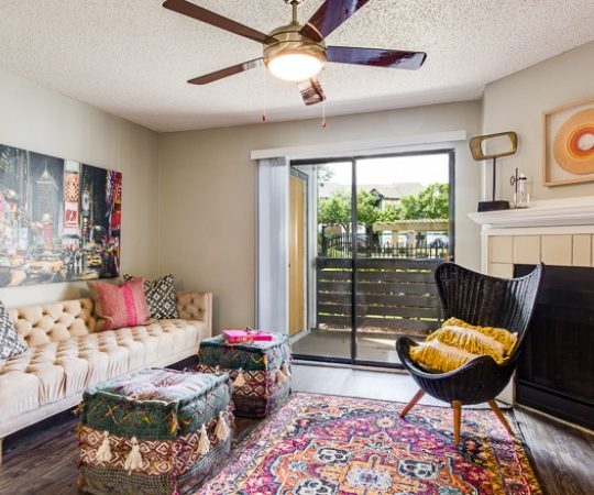 a living room with a rug, couch, and a fan at The Lorenzo