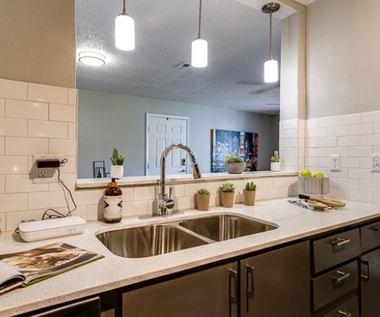 a kitchen with a sink, counter and light fixture at The Lorenzo